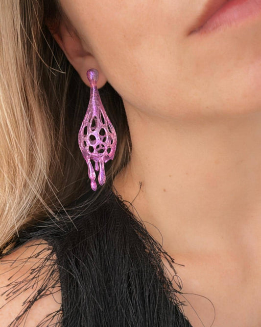 Close-up of pink earrings worn by a person with dark hair.