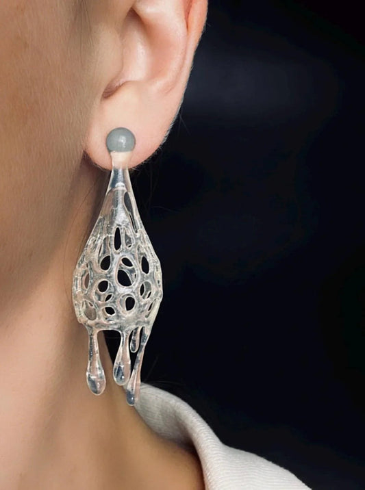 Close-up of futuristic sculptural earrings worn on the ear.