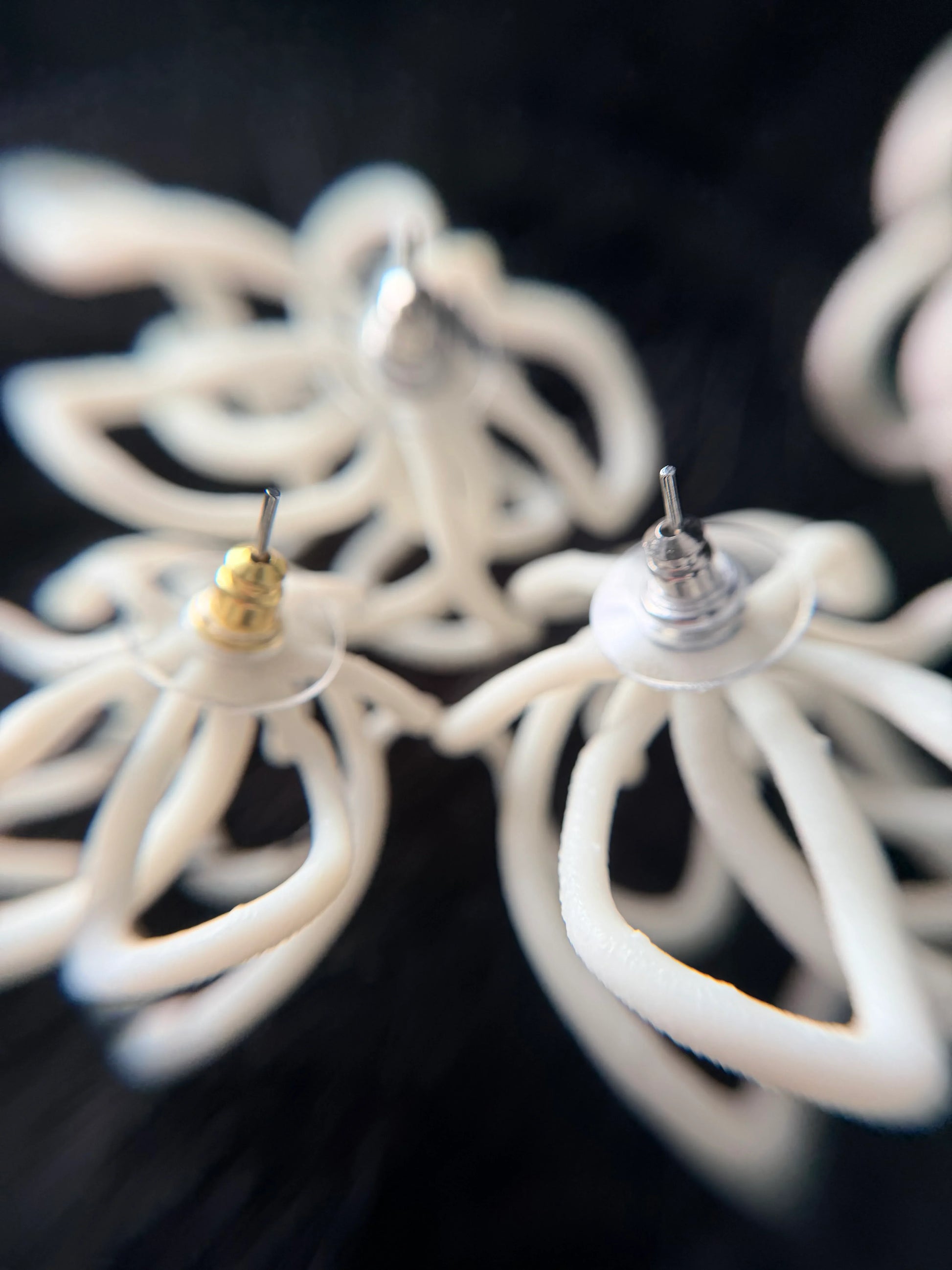 Close-up of sculptural white jewelry earrings from Eclipse Element on black background