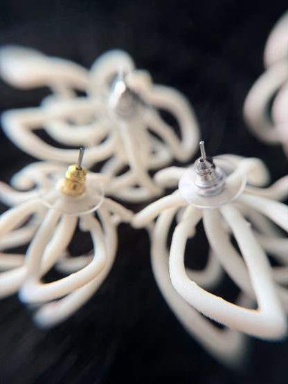 Close-up of sculptural white jewelry earrings from Eclipse Element on black background