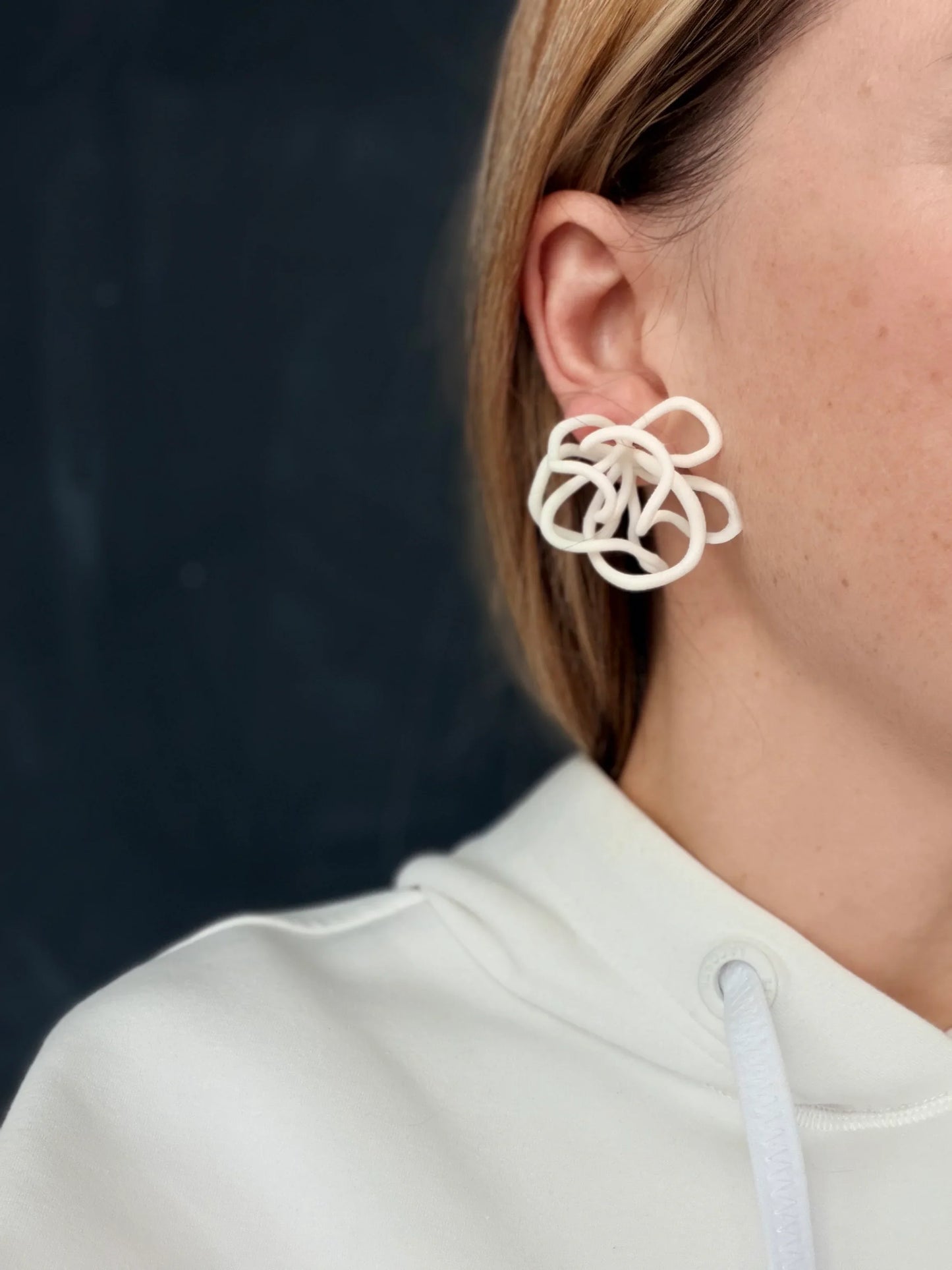 Woman wearing Eclipse Element sculptural white statement earring, close-up view