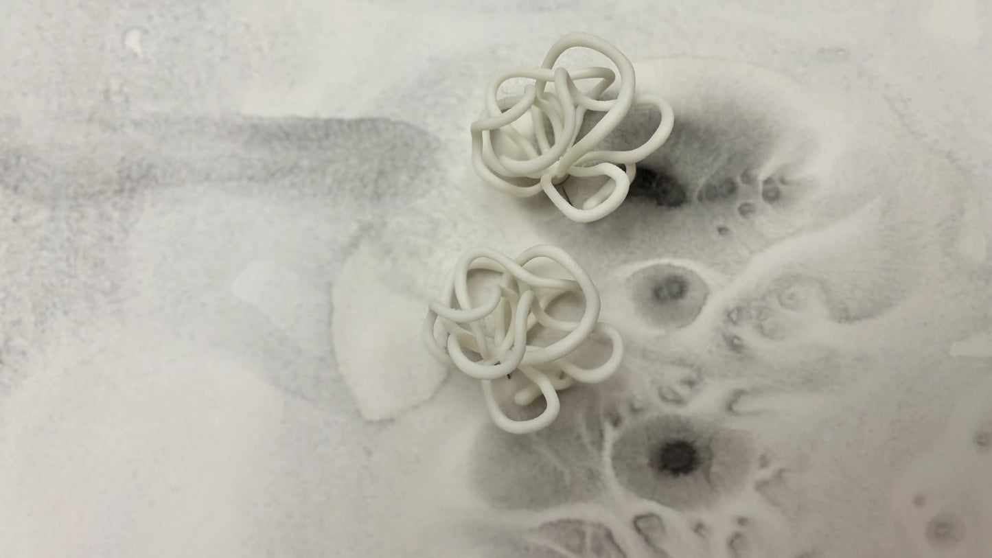 Handcrafted sculptural white earrings by Eclipse Element on abstract grey background