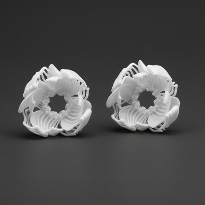 Two large, complex 3D printed stud earrings shaped like voluminous white flowers, resting on a black background.