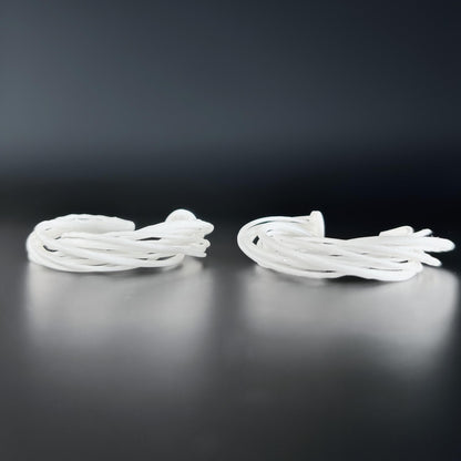 Two large white 3D printed Swirl Hoop Earrings, resting side-by-side on a dark, reflective surface.