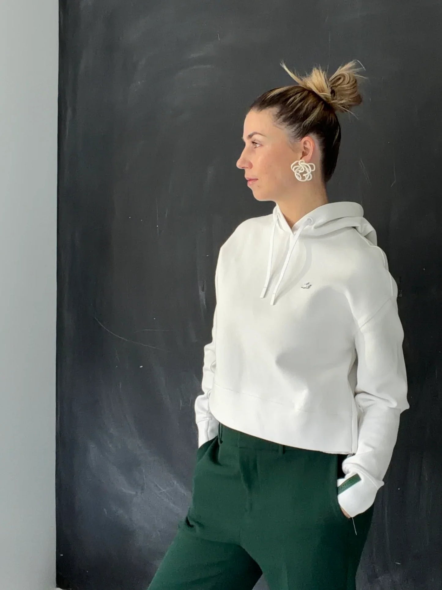 Woman wearing sculptural statement earrings and white hoodie, Eclipse Element jewelry