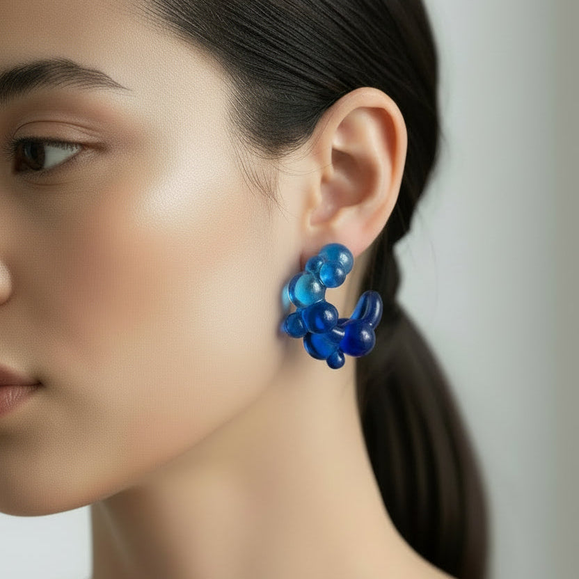 Blue bubble-shaped hoop earrings on a white background