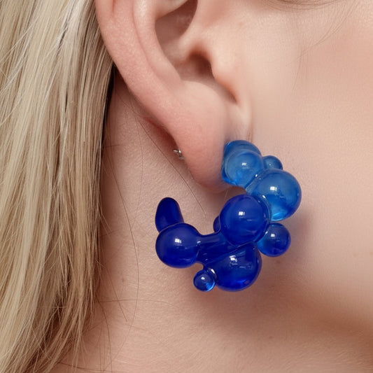 Blue balloon earrings worn by a person