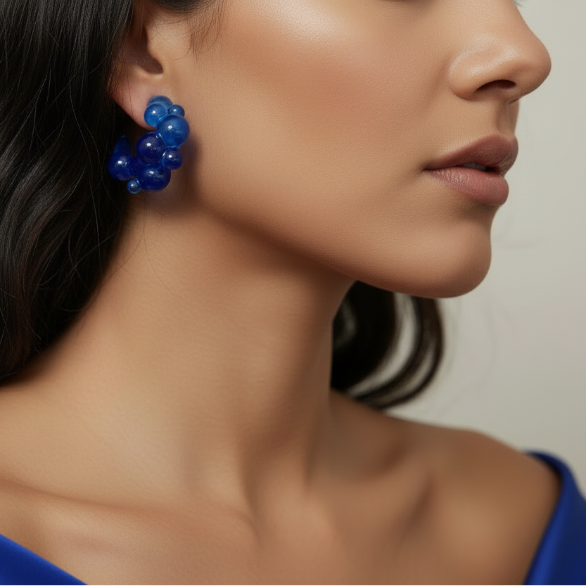 Blue balloon earrings worn by a person