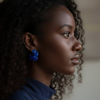 Woman wearing blue floral earrings with a blurred background