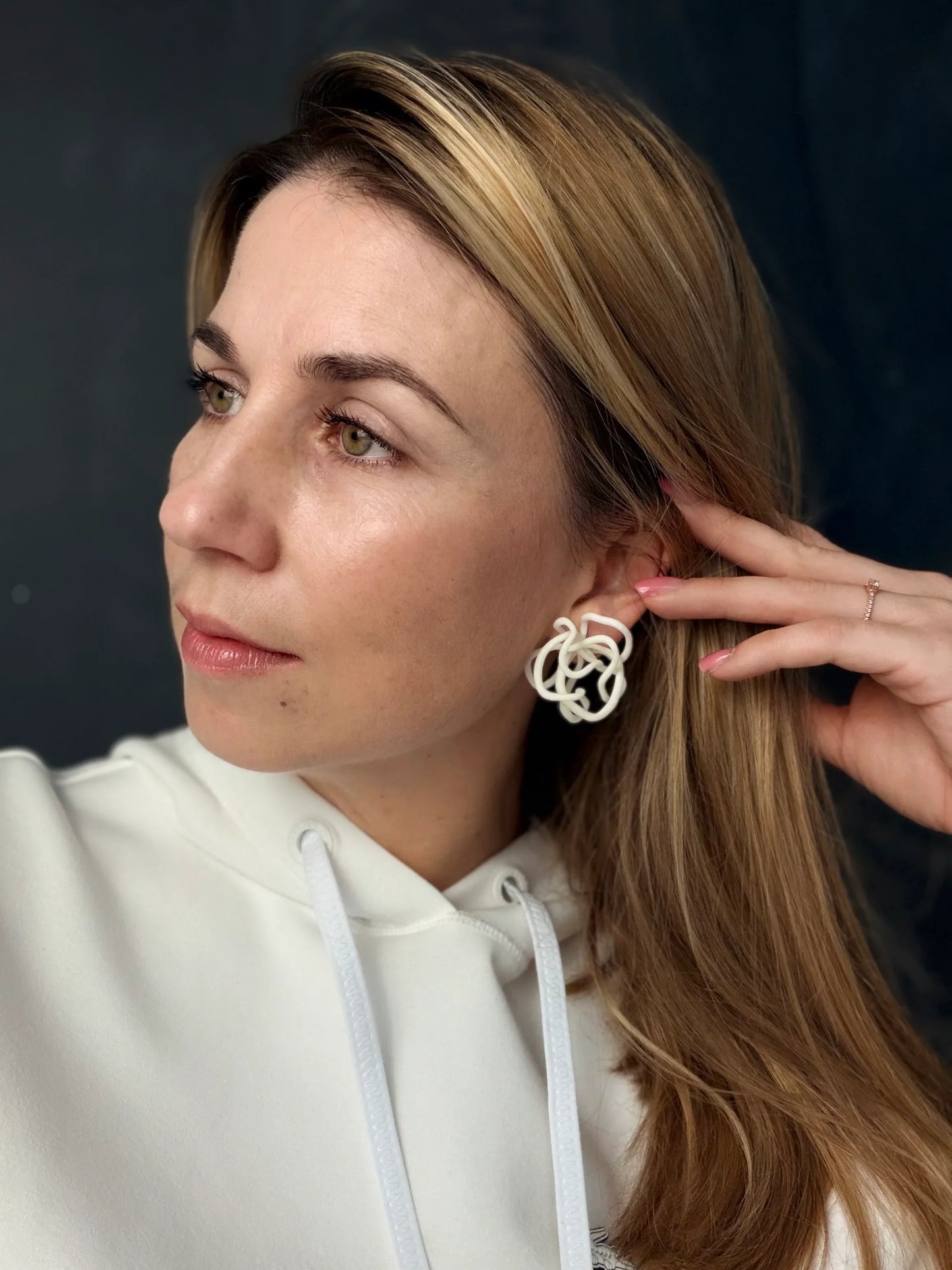 Woman wearing handcrafted sculptural white earring from Eclipse Element jewelry