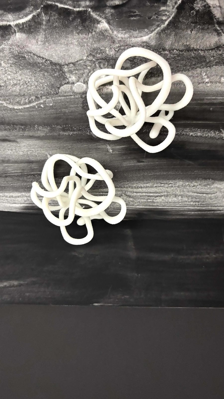 Abstract white sculptural earrings on a marbled black and gray background, Eclipse Element jewelry