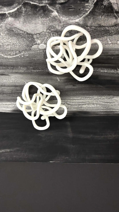 Abstract white sculptural earrings on a marbled black and gray background, Eclipse Element jewelry