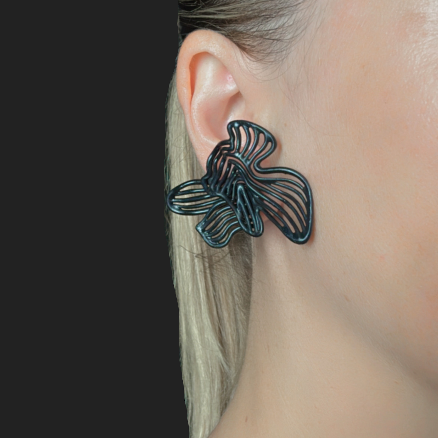Black butterfly-shaped earring worn by a person with a black
background