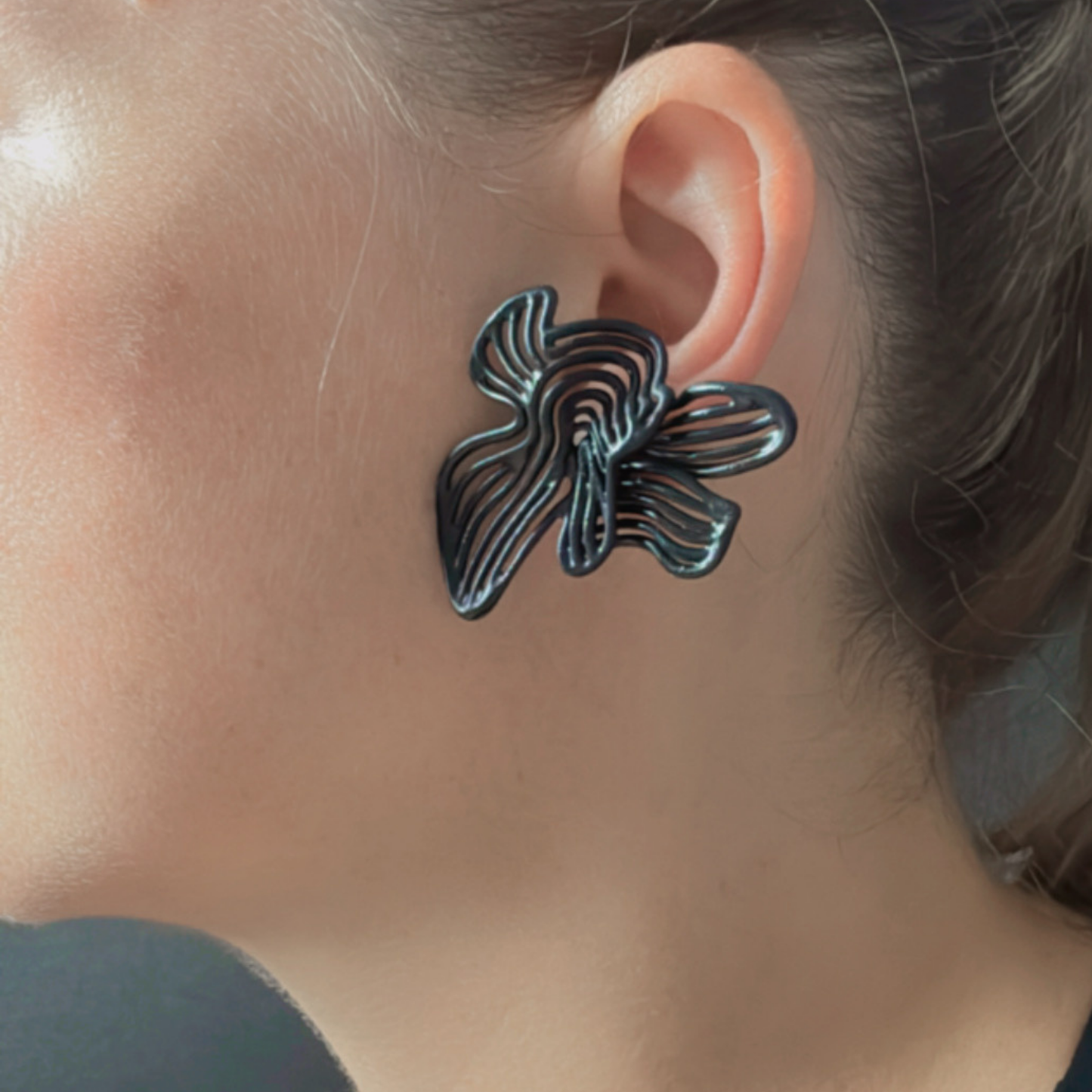 Black bold  floral earring worn by a person