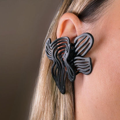 Black  large  floral earring worn by a person.