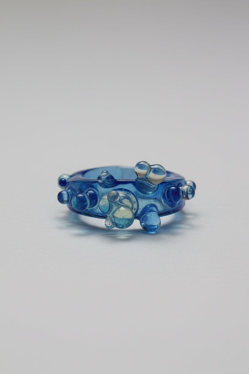 Blue glass ring with bubble design on a white background