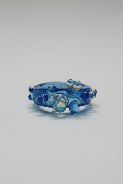 Blue glass ring with bubble design on a white background