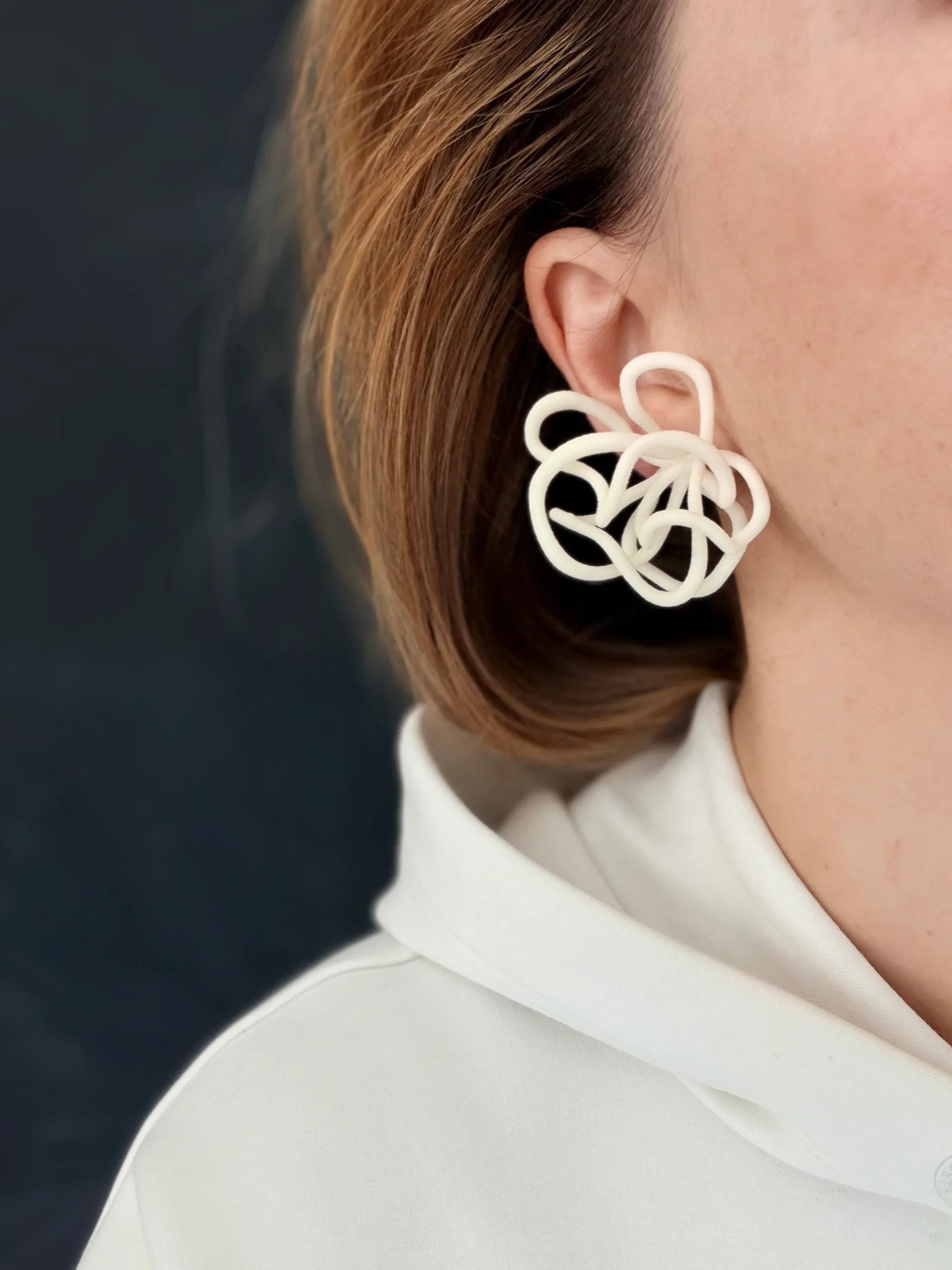 Handcrafted sculptural white statement earring by Eclipse Element, worn with white top.