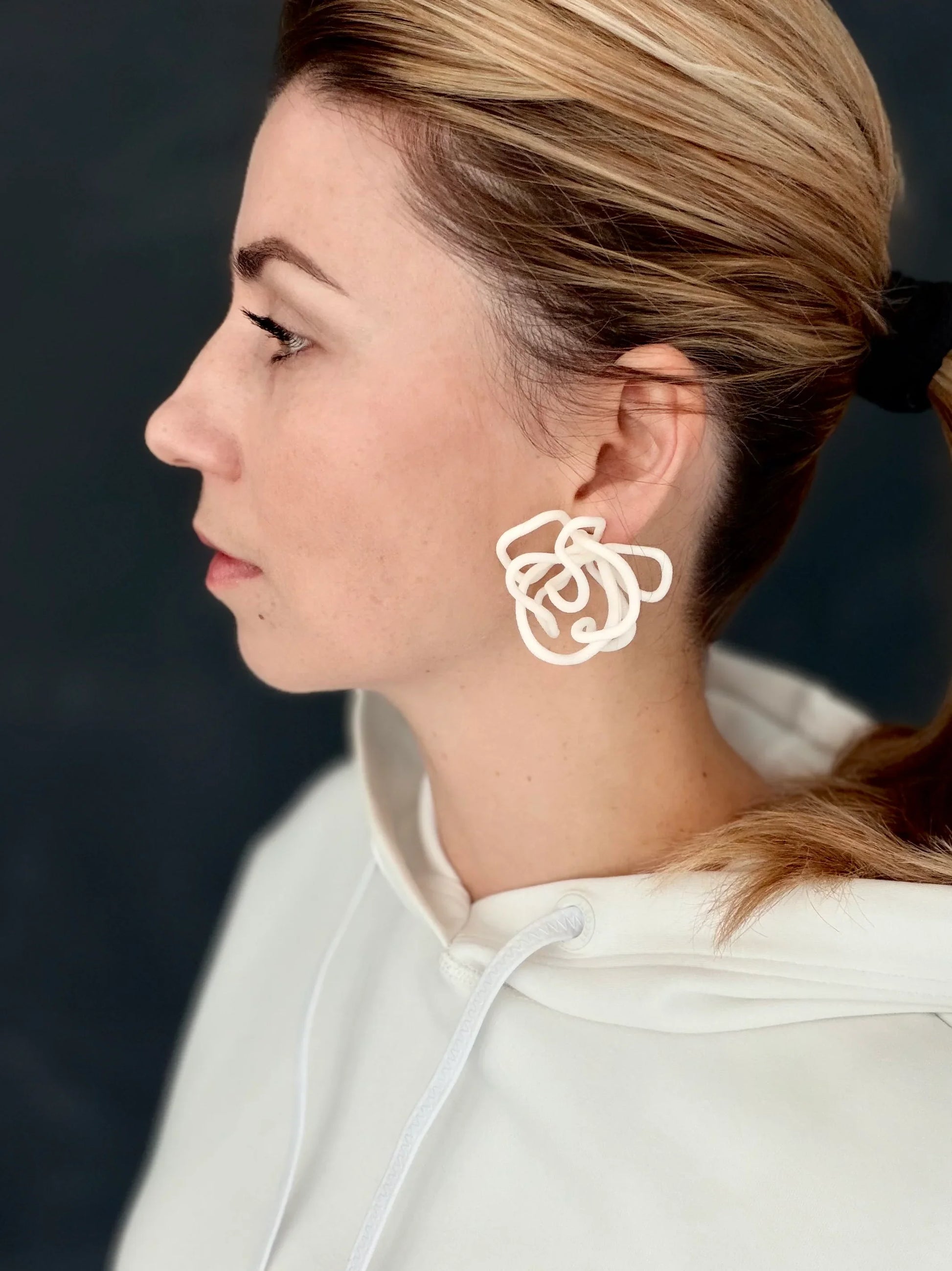Woman wearing sculptural white statement earring by Eclipse Element, side profile view.