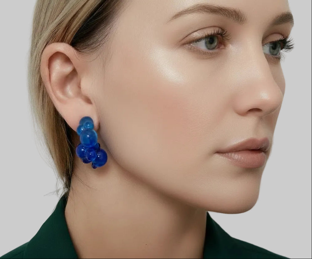 Blue earrings worn by a person with a neutral background