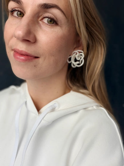 Woman wearing sculptural handcrafted white earrings by Eclipse Element, white hoodie, close up