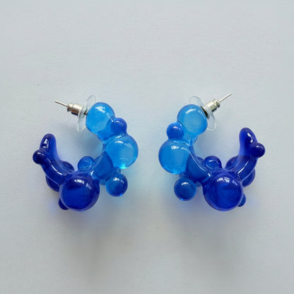 Pair of blue balloon-shaped earrings on a light gray background