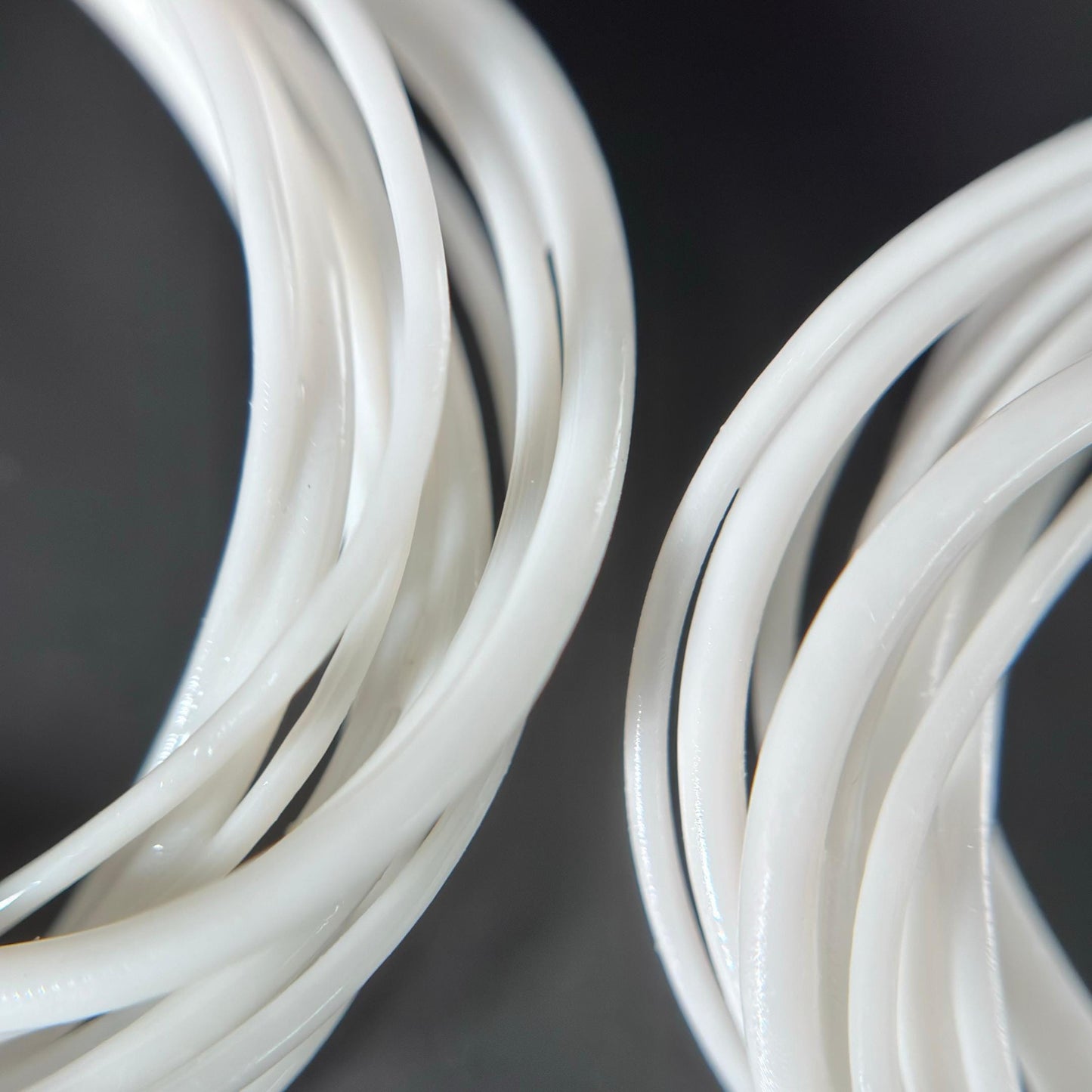 Extreme close-up detail of the intricate, layered, white photopolymer strands that form the 3D printed Swirl Hoop earring.