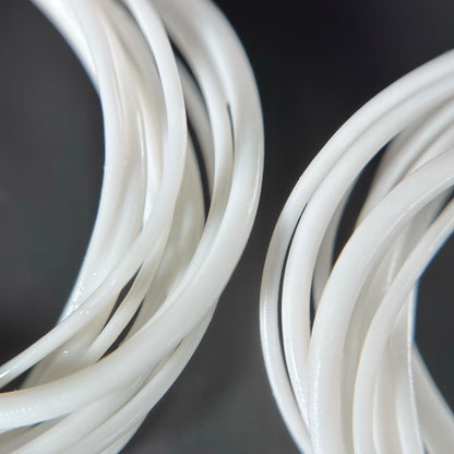 Extreme close-up detail of the intricate, layered, white photopolymer strands that form the 3D printed Swirl Hoop earring.