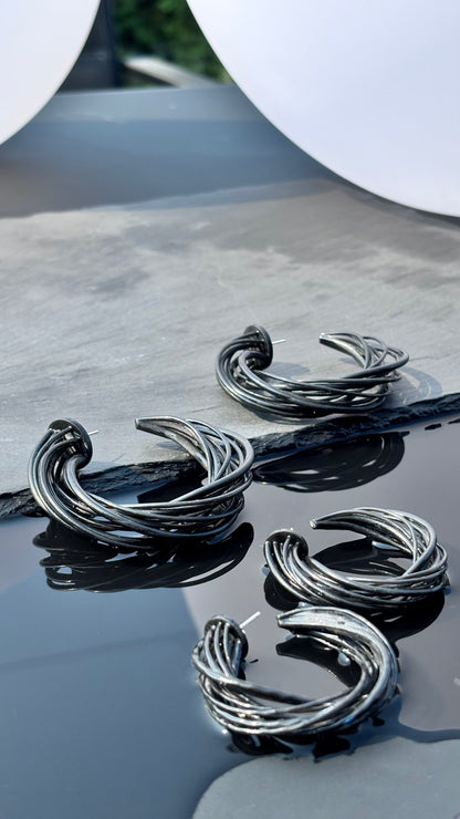 black hoop earrings on a reflective surface with a blurred background