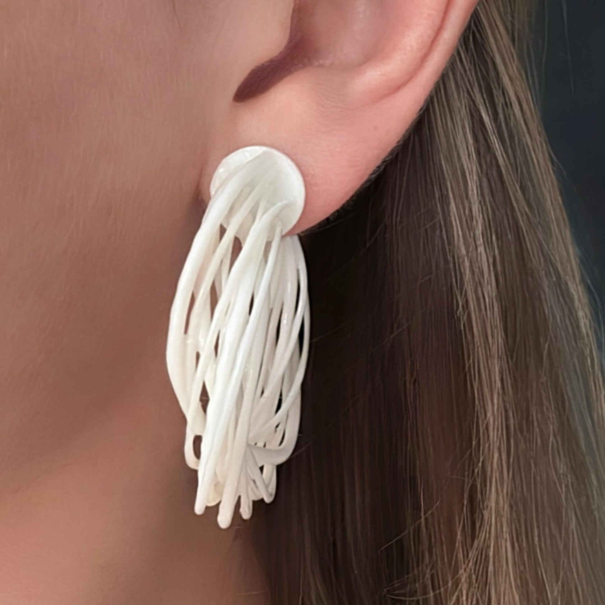 Close-up of a model's face, showcasing a large white 3D printed Swirl Hoop Earring from the side, highlighting the layered texture.