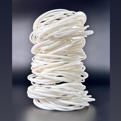 A white 3D printed Swirl Hoop Earring displayed standing upright, showing its layered, cylindrical form, against a dark background.