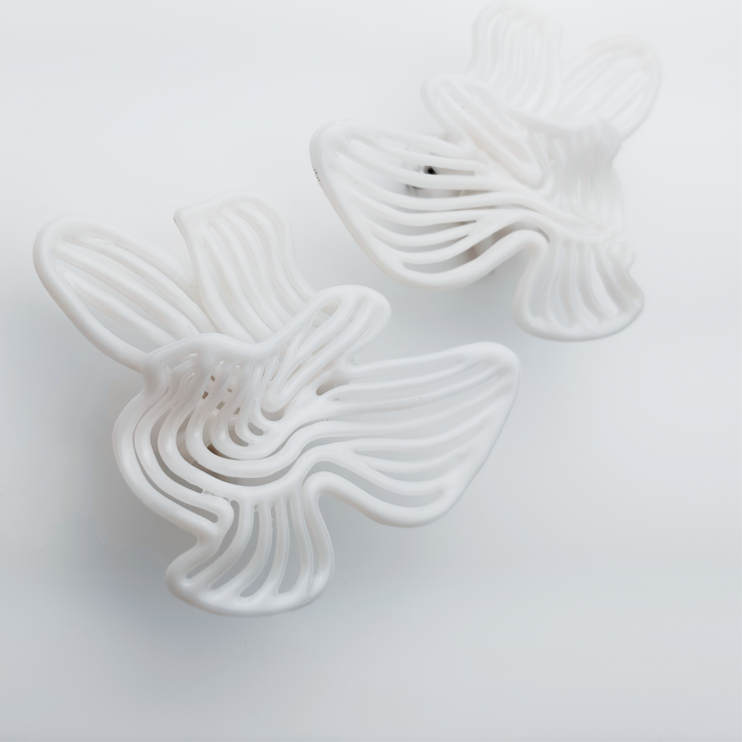 White large  floral statement earrings on a light gray background