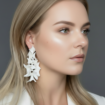 Woman wearing white floral earrings against a gray background
