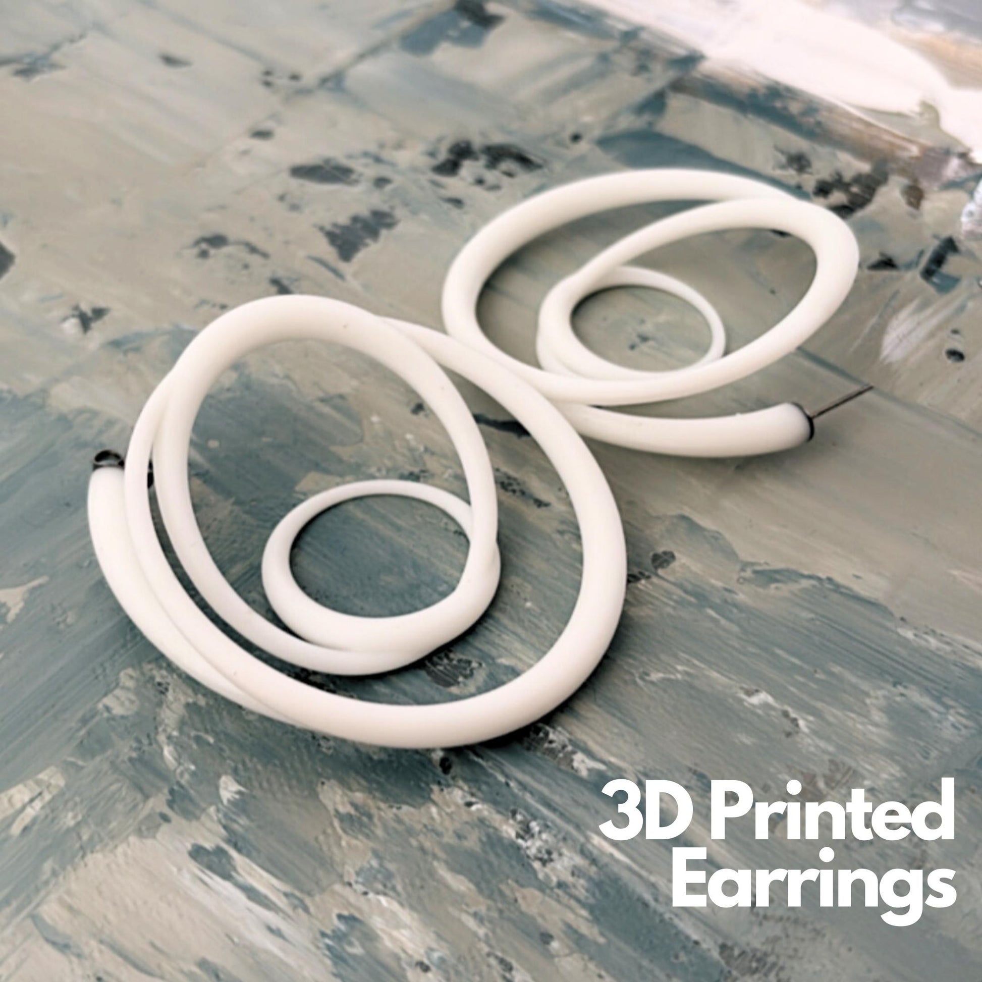 White sculptural swirl hoops 3D printed recycled resin on a textured background