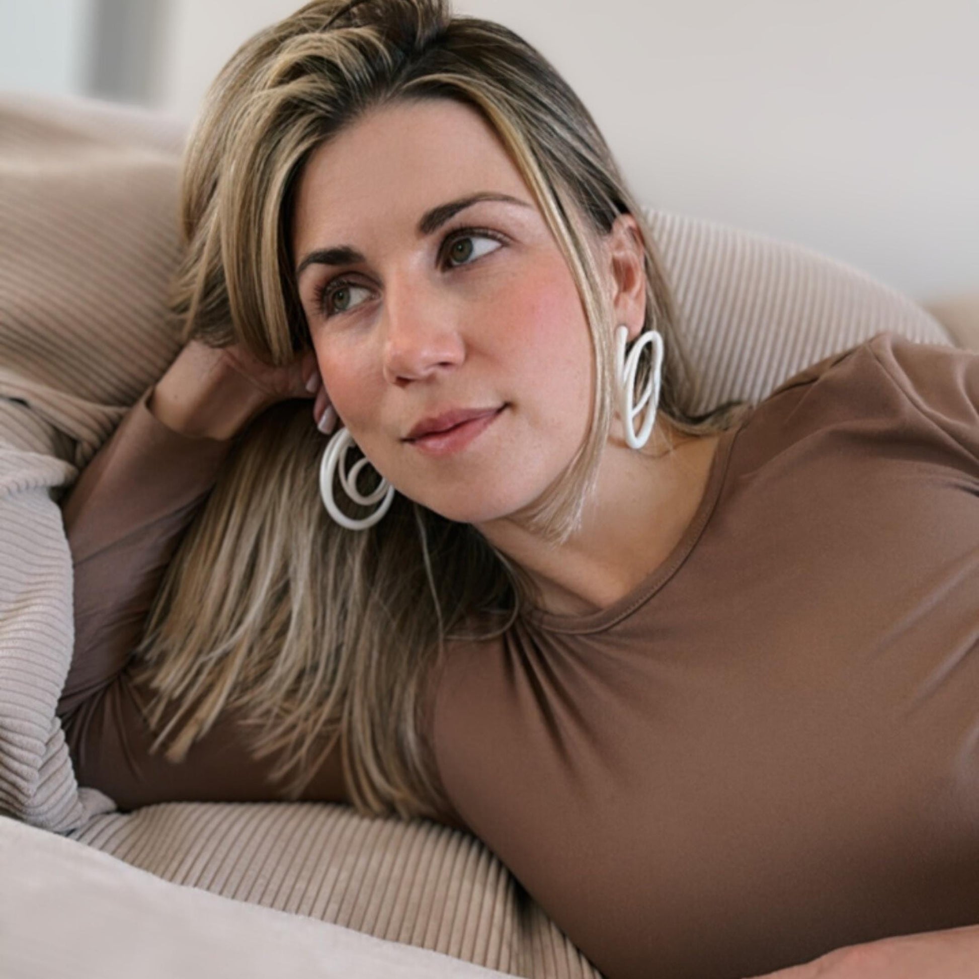 Model wearing white swirl hoops showing the bold size and hypoallergenic post