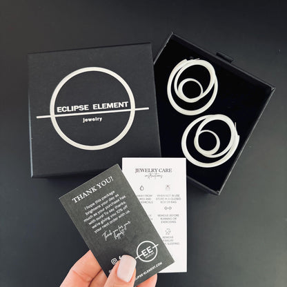 Swirl Hoops displayed with Eclipse Element branding and jewelry care instructions