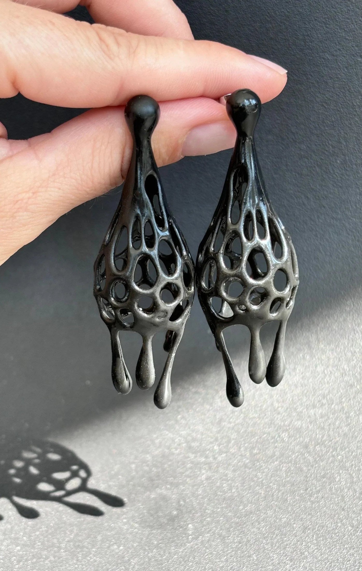 Hand holding bold statement earrings, demonstrating the lightweight black tie statement earrings design.