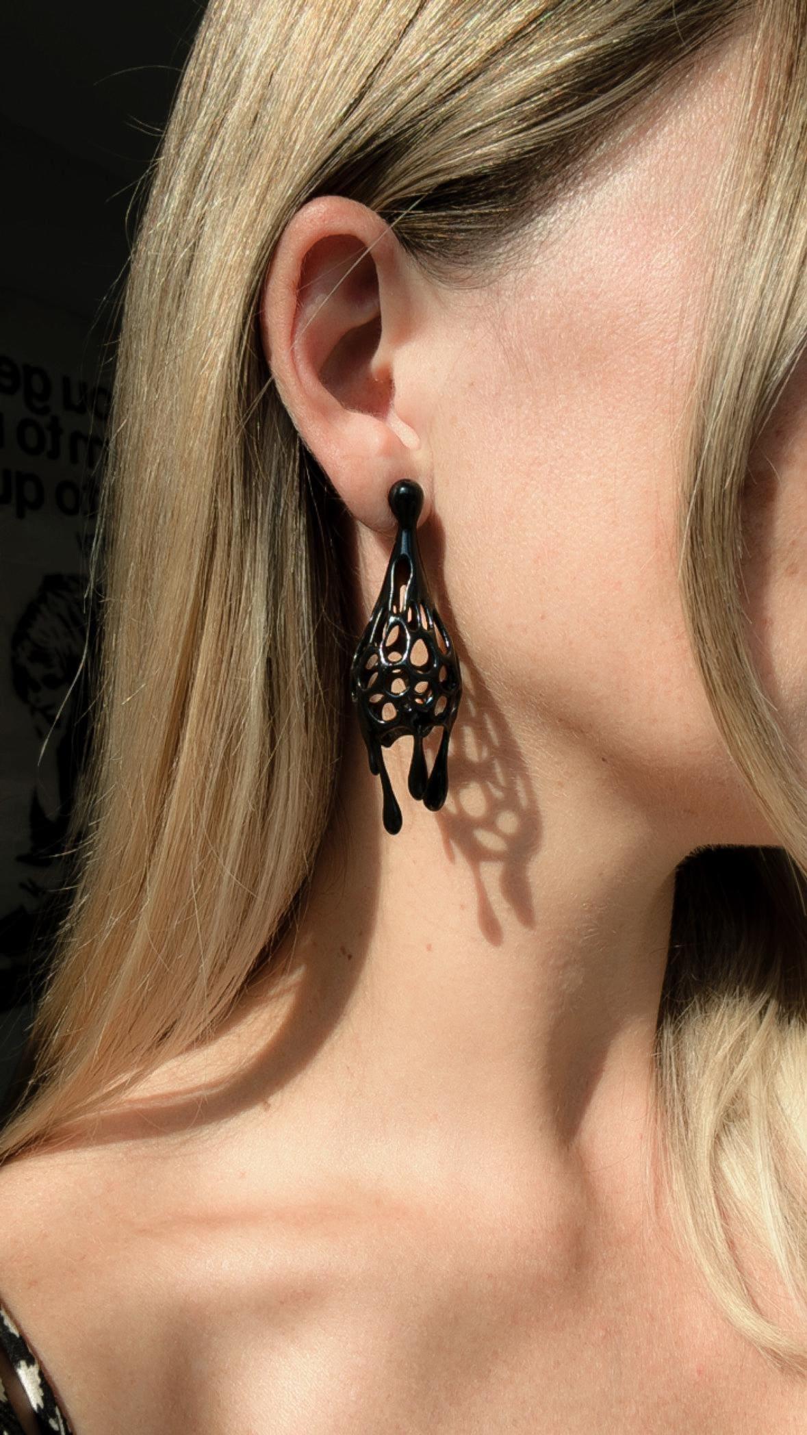 Model showing how to wear statement earrings in a black drip sculptural style.