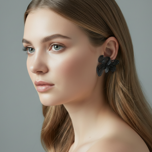 Woman wearing a black floral earring against a gray background