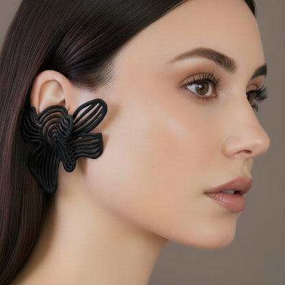 Close-up of black statement earrings on model's ear, showing the rhythmic detail.