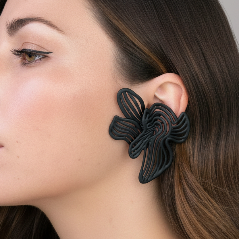 Woman wearing a black floral earring against a neutral background