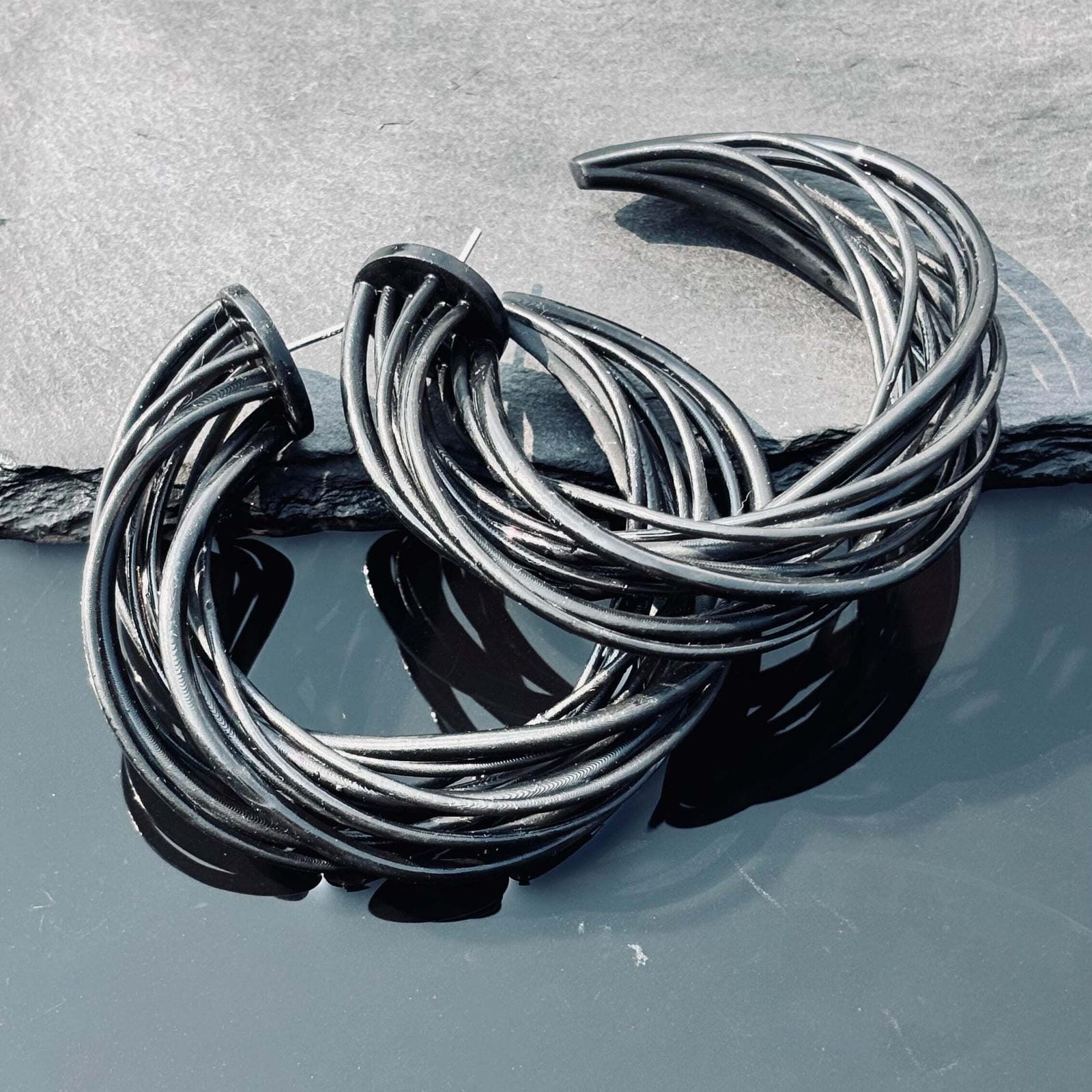 Studio shot of geometric black jewelry, highlighting the light-reflecting matte finish
