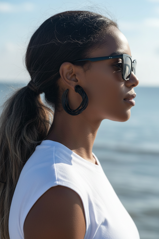 Woman wearing sunglasses and a white top with a blurred ocean background