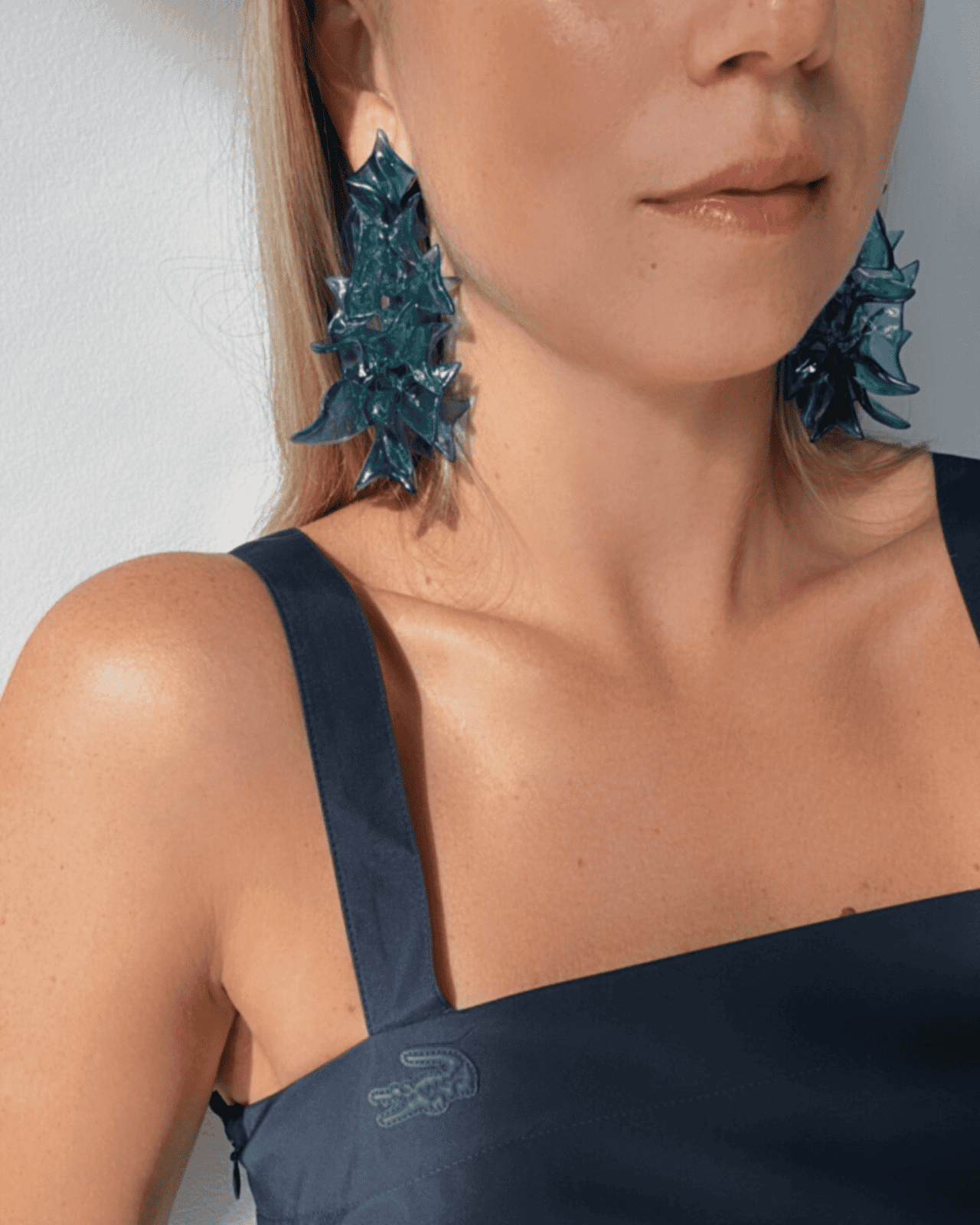 Bright statement earrings worn, showcasing the scale near the face.