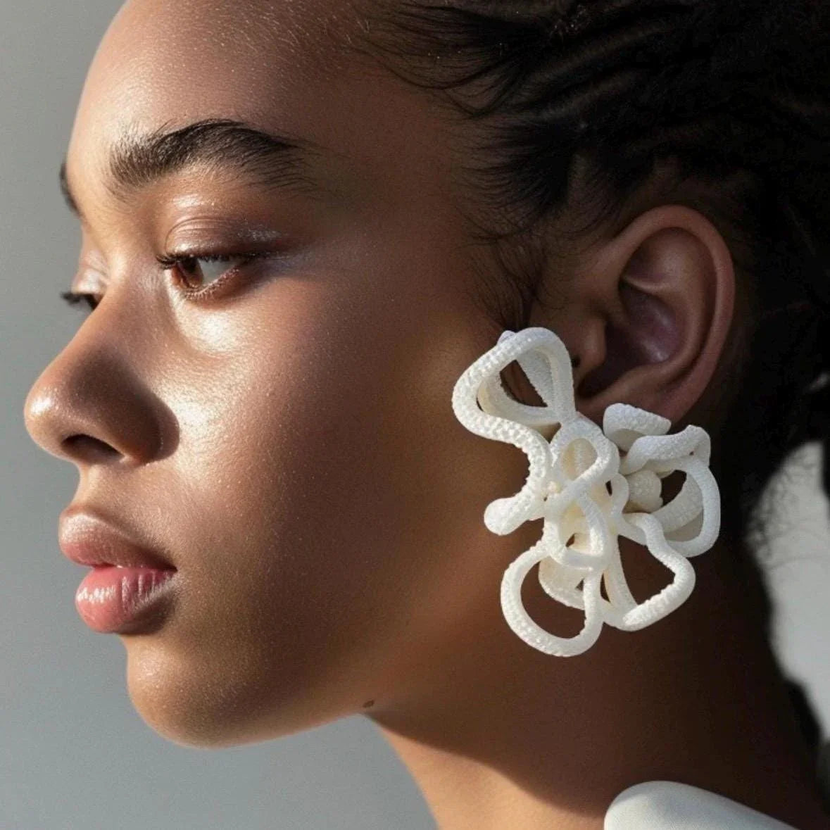 White custom color earrings displaying modern abstract loops.