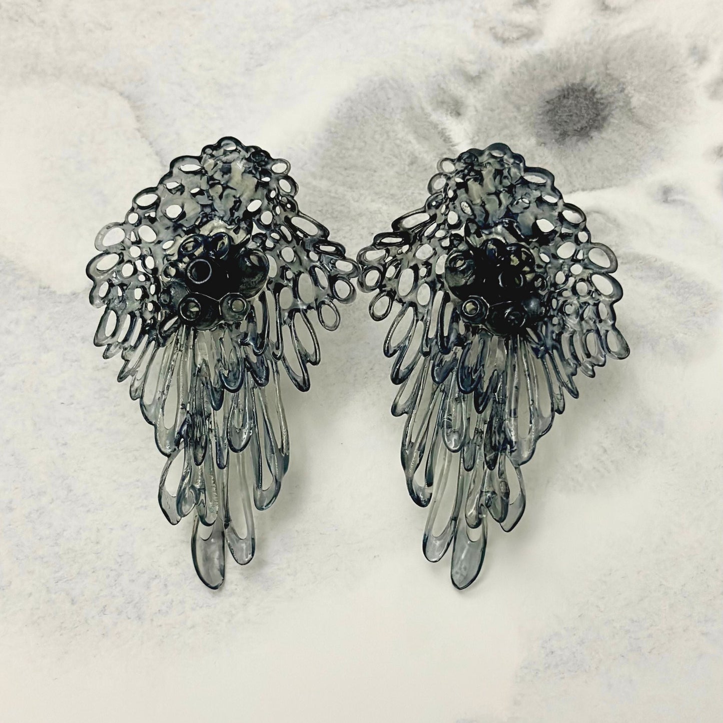 Pair of black Coral Lace earrings on white textured background, main product shot