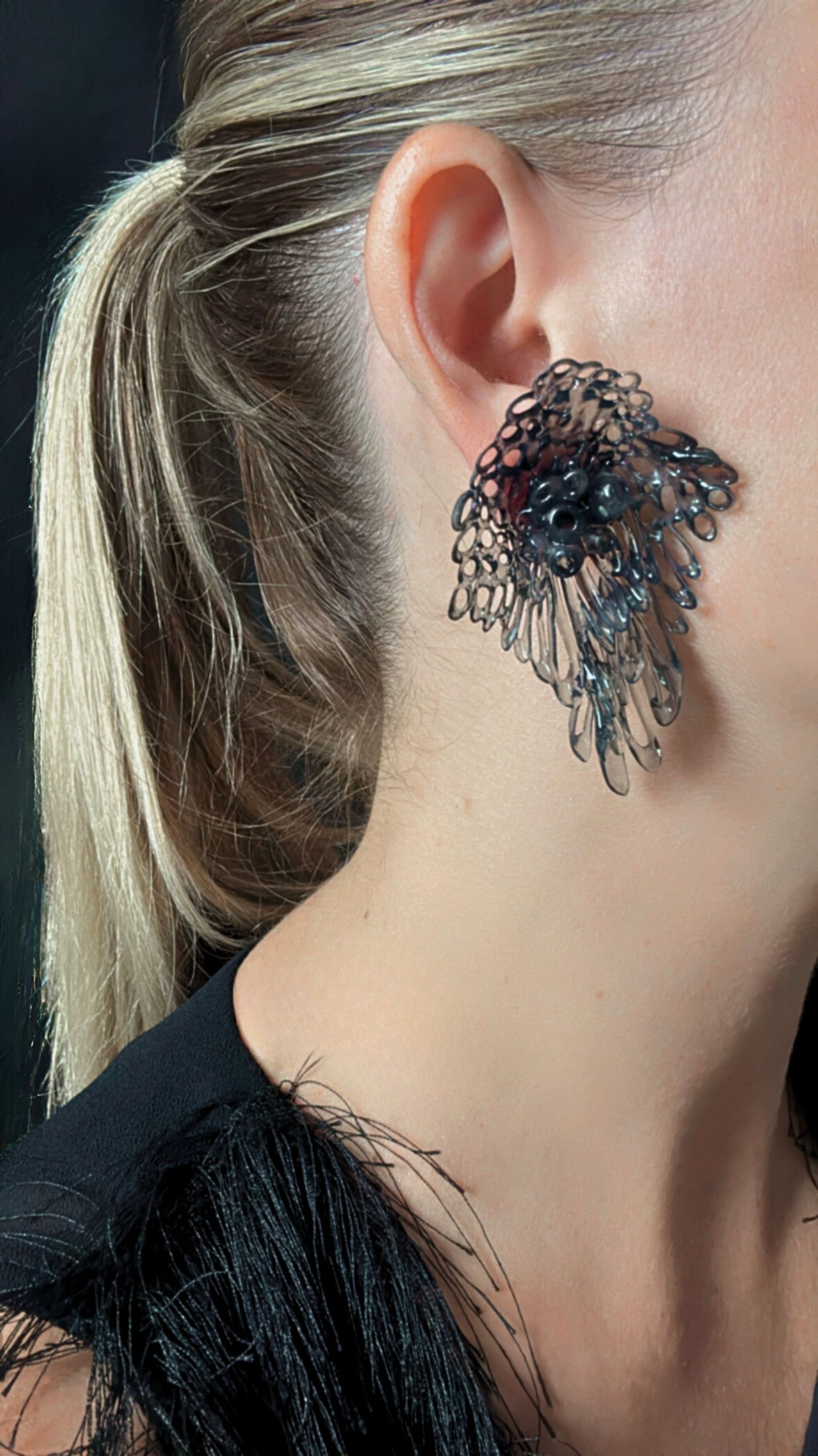 Close-up of model wearing black Coral Lace earrings, focusing on the earlobe and neck line