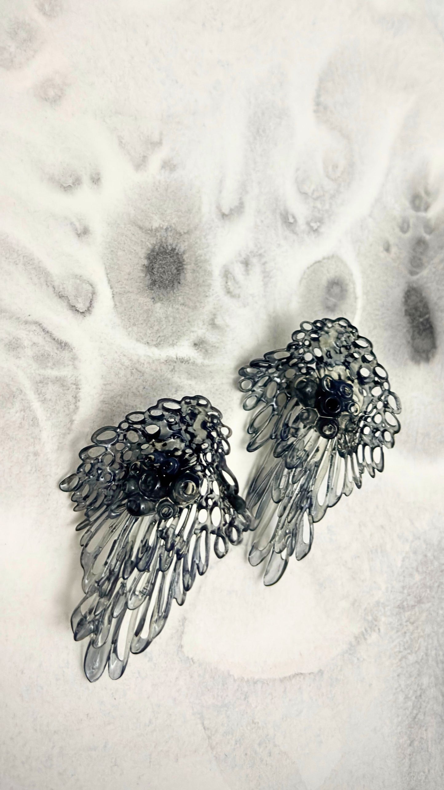 Close-up of Coral Lace earrings on textured surface, showing the photopolymer resin detail