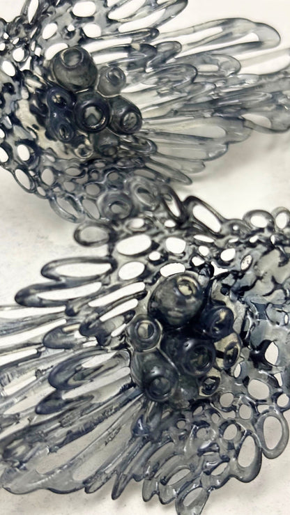 Detailed view of the organic coral-like holes in the sculptural earrings.