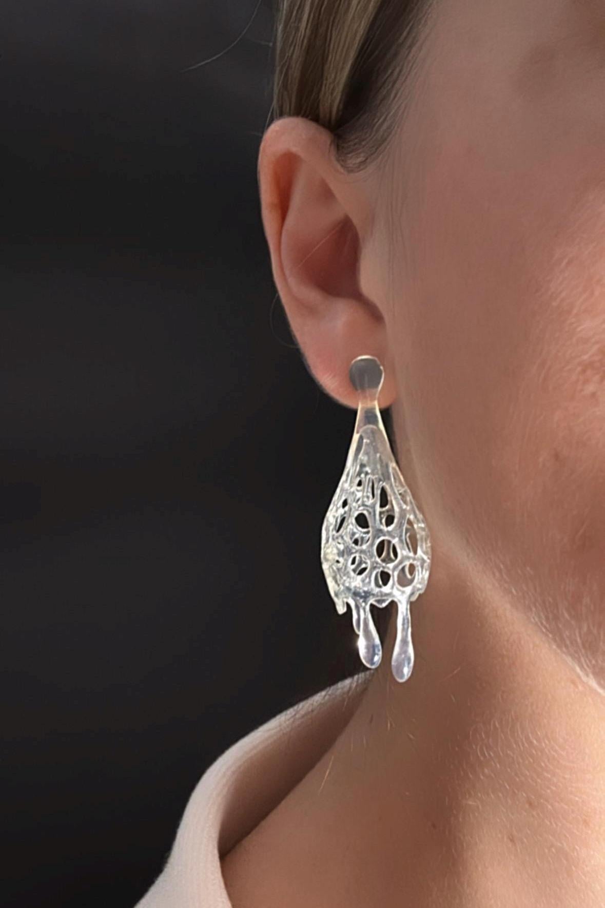  crystal drop 3d printed earrings worn by a person with a dark background.